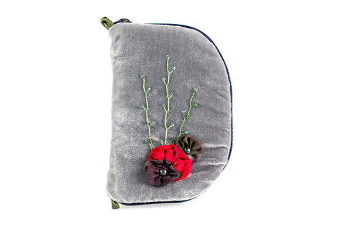Front view of grey velvet jewelry/sewing case with a silk floral arrangement attached. A cherry red flower is featured in the middle with two brownish purple flowers on either side. Each brown flower has a Freshwater pearl placed in the center. Three beaded vines go above the flowers. There is a dark blue zipper and two small green loops one situated at the top and one at the bottom. 