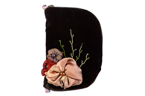 Front view of dark brown velvet jewelry/sewing case. The front features three silk flowers, one a light mocha brown color, one brownish purple, and one rusty red. Each flower has a freshwater pearl in the center. There are beaded vines embroidered around the flowers. There are two small loops, one at the top and one at the bottom made from silk that is a gradient of colors, from purple to pink, to green. The zipper is dark brown. 