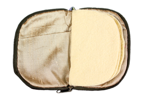 Interior view of jewelry/sewing case showing a gold lining and pockets and cream colored felt pages. 