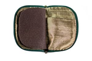 Interior view of jewelry/sewing case, showing dark gold lining and pockets, and dark brown pages.