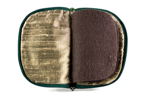 Interior view of jewelry/sewing case, showing dark gold lining and pockets, and dark brown pages. 