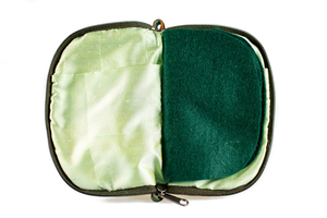 Interior view of jewelry/sewing case showing shimmery light green lining and pockets and dark green felt pages. 