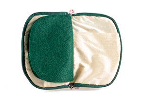 Interior view of jewelry/sewing case showing cream colored lining and pockets with dark green felt pages.