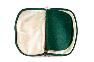 Interior view of jewelry/sewing case showing cream colored lining and pockets with dark green felt pages. 