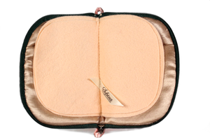 Interior view of jewelry/sewing case showing champagne colored lining and pockets and peach colored pages. 